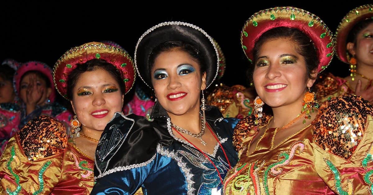 Three women in traditional dress at the Virgen de la Candelaria Festival in Puno. Image by Monica Volpin from Pixabay.