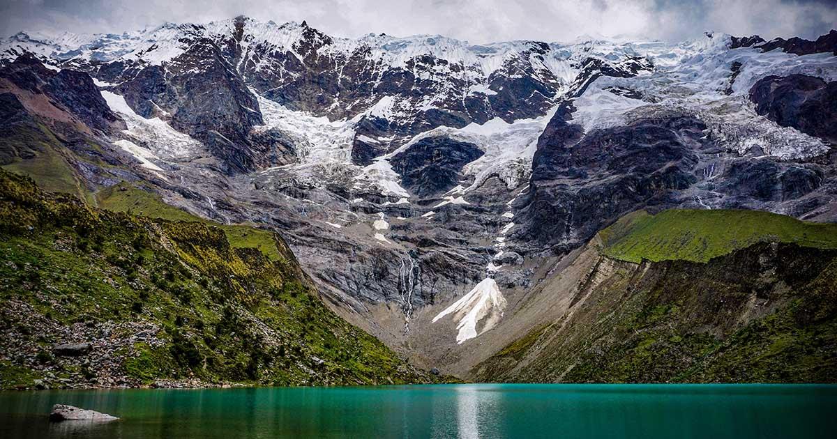 Snow-capped mountains loom over the blue-green waters of Humantay Lake. Photo by Giacomo Buzzao on Unsplash.