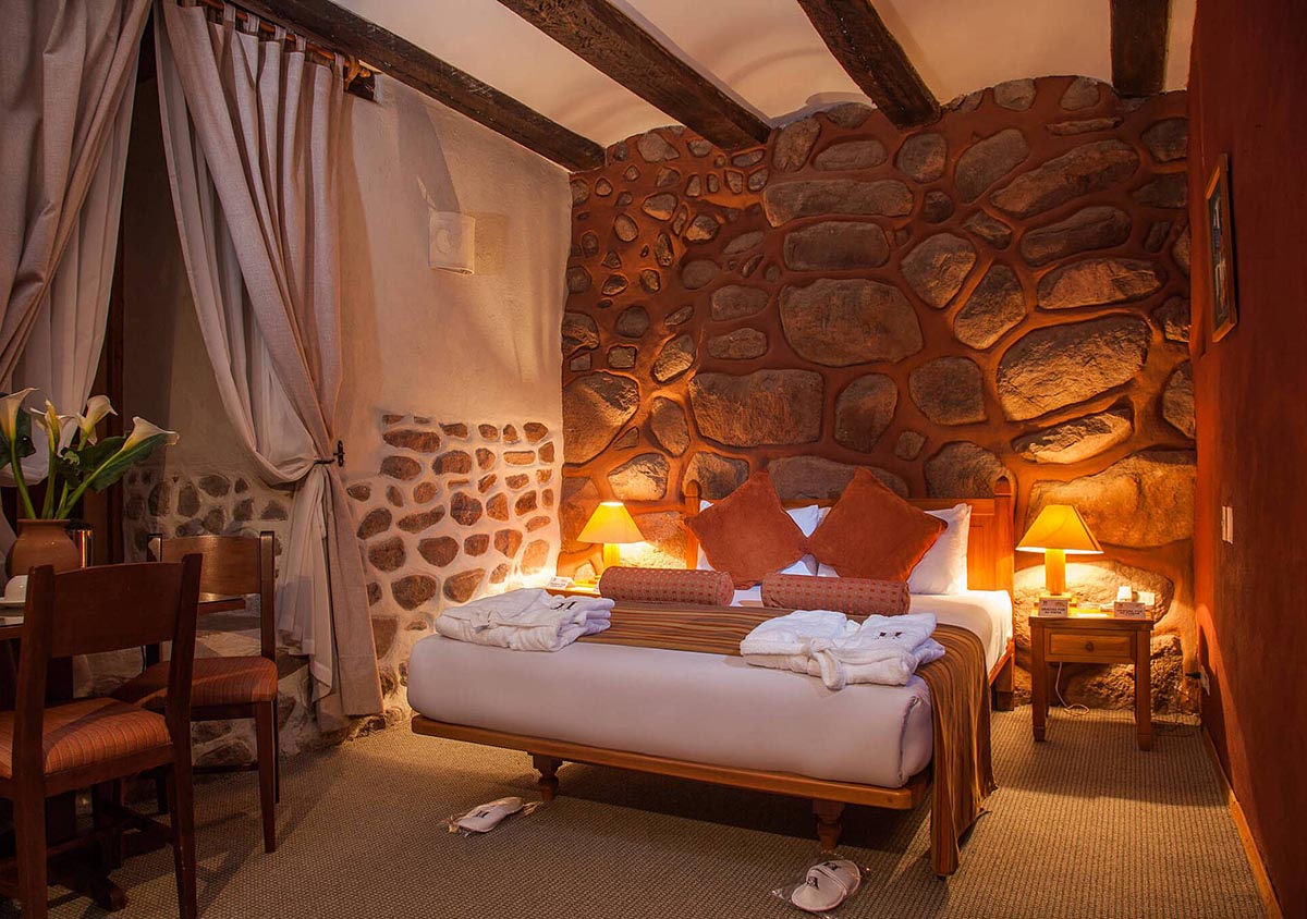 Guest room at Hotel Monasterio de la Recoleta, with Andean textile, stone accents and exposed wood