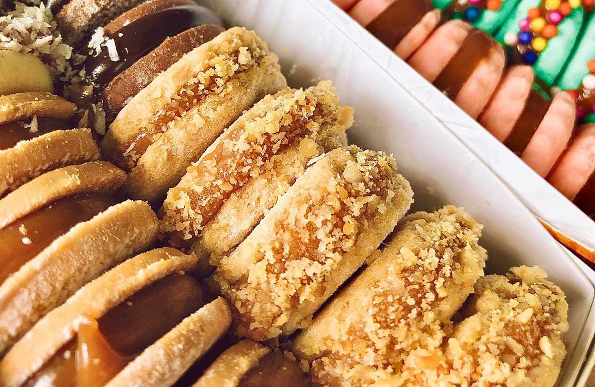 A box stacked with alfajores, circular shaped sugar cookies sandwiching a caramel filling