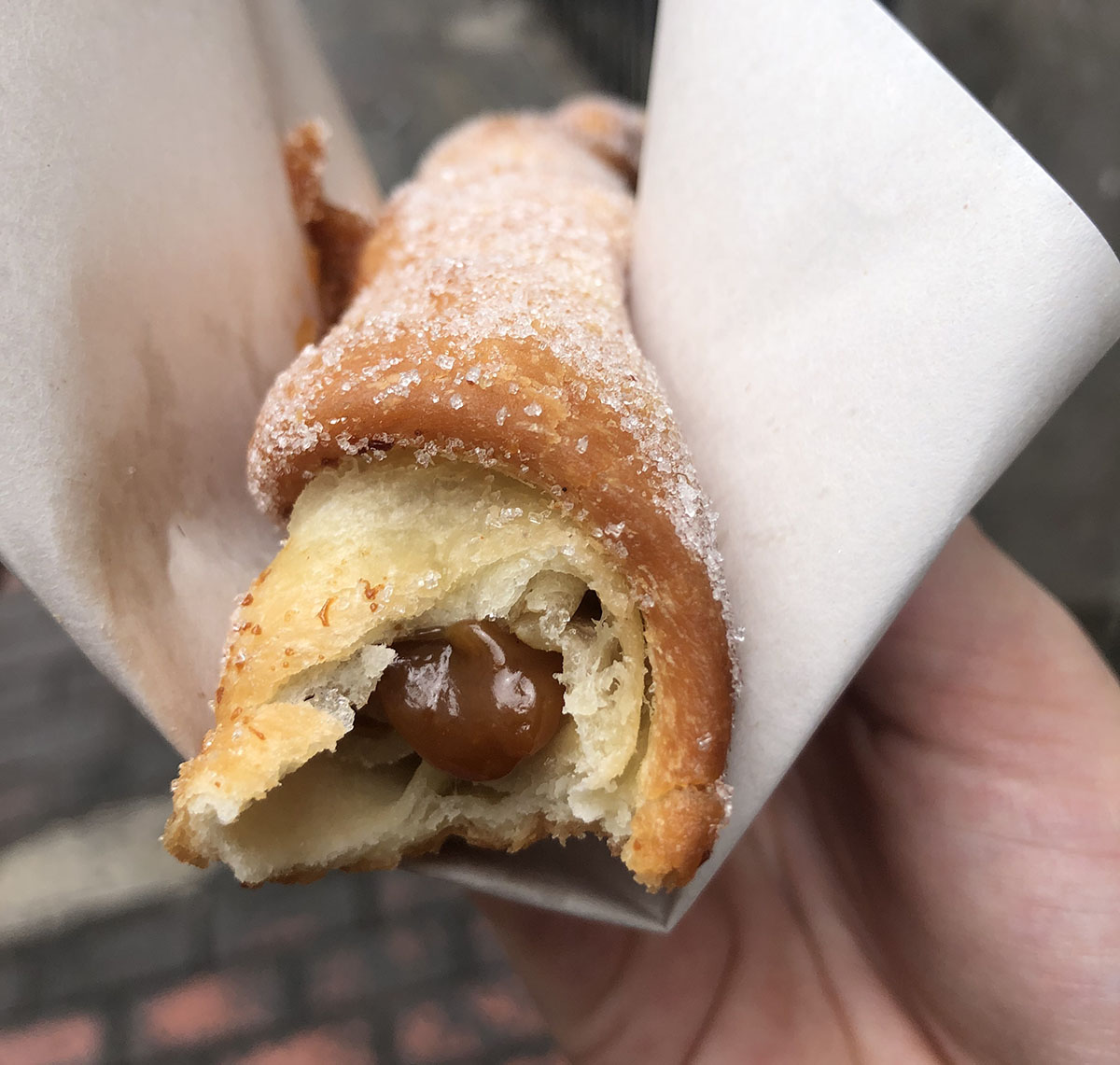 Gooey caramel coming out of a deep fried doughy churro covered in sugar