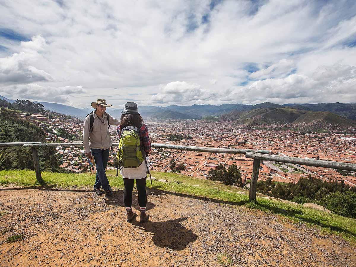 Cusco tour guide talking with a traveler at a lookout point over the city of Cusco.