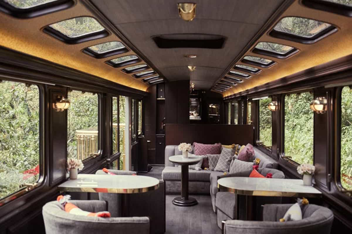 The inside of the Inca Rail Private Train to Machu Picchu with tables and comfortable couches.
