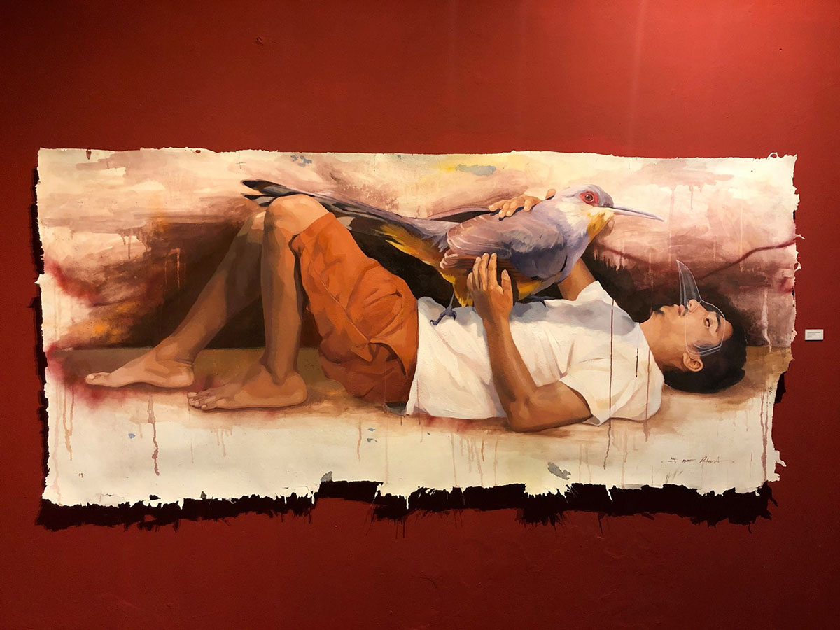 A realistic painting of a man lying on his back with a large bird standing on his stomach.