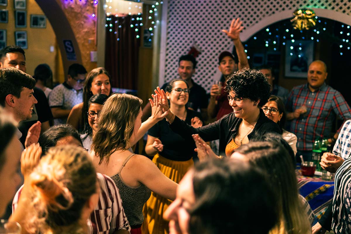 A group of people dancing and smiling on the dance floor of Peña La Oficina in Lima.
