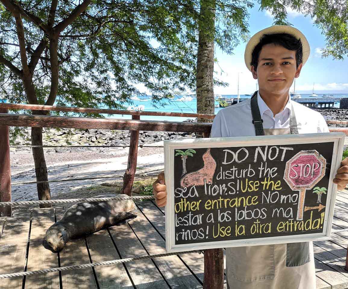 Ecuadorian man holding a sign with rules for respecting the wildlife in the Galapagos.