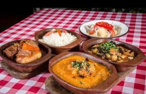 A red and white checkered tablecloth with 5 dishes of food