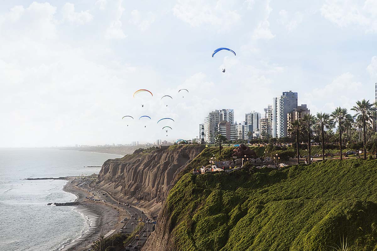 Paragliders in Lima soar over green cliffs, with views of the ocean and the city skyline