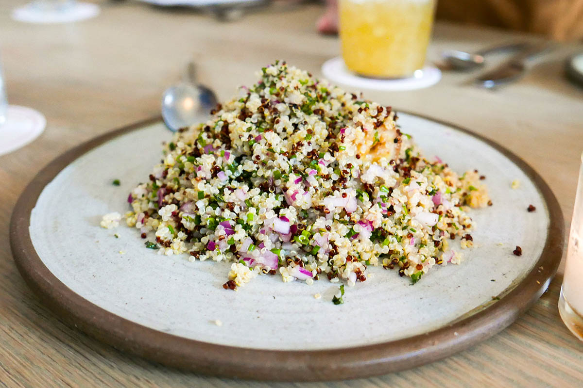 Quinoa salad made with white and black quinoa and minced onions on a white plate.