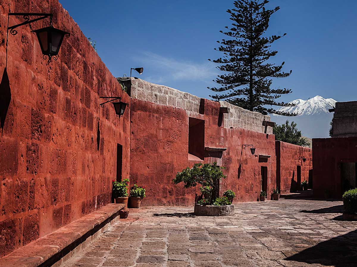 Red walls of the Santa Catalina Monastery with the snow-covered Misti Volcano in the background.