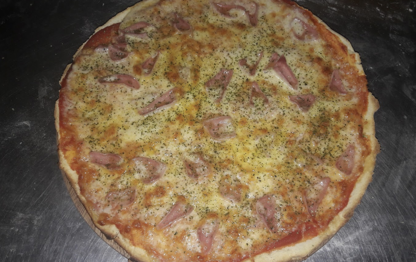 A full gluten free pizza topped with ham and black pepper