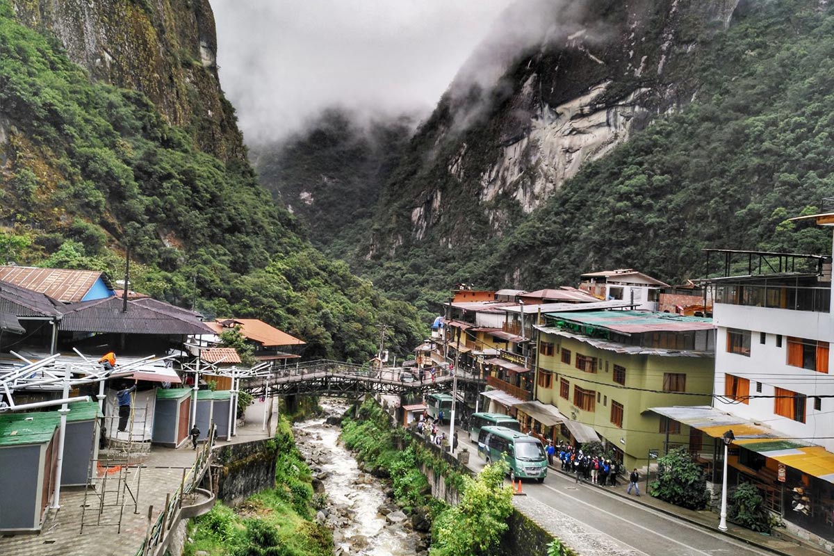 The colorful town of Aguas Calientes and travelers lined up at the street bus stop.
