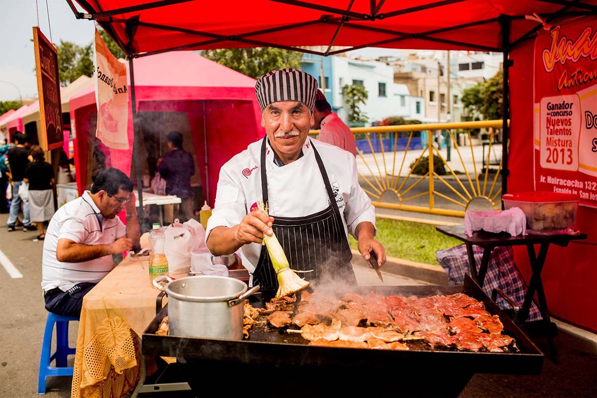 Man in chef's outfit and apron making anticuchos at the famous Mistura Food Festival in Lima, Peru