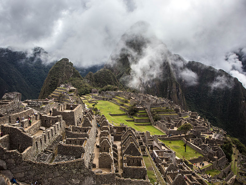 The ruins of Machu Picchu with the sky and the mountains partially shrouded in fog.