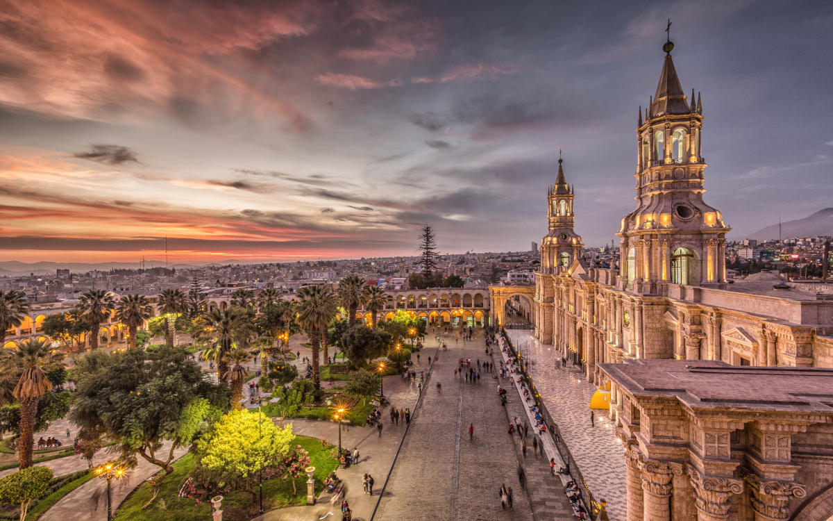 The Plaza de Armas of Arequipa during sunset with pink and purple skies.