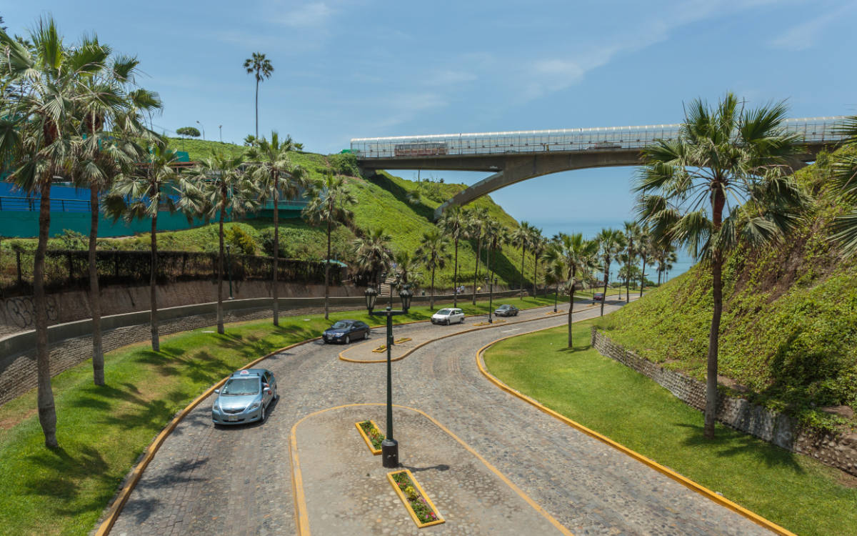 Lightly trafficked cobbled road in Miraflores with trees on the sides leading to the Pacific Ocean.