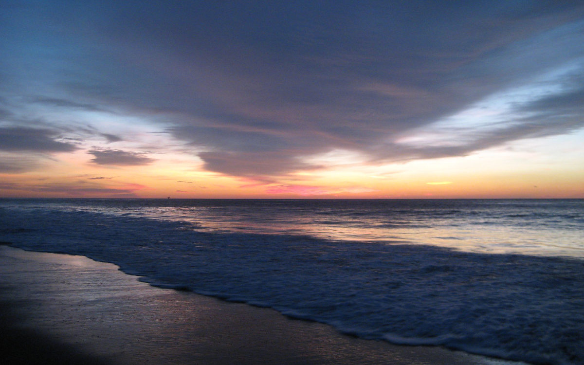 An orange, purple and red sunset over the Pacific Ocean in Mancora, Peru, a popular beach town.