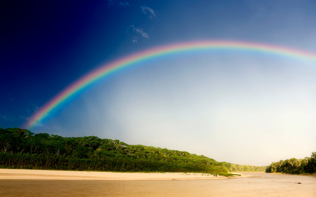 Rainbow arching over the river and southern Amazon Rainforest of Peru.