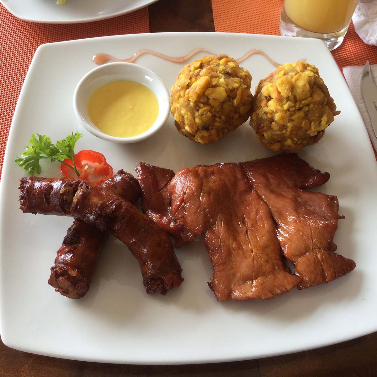 Grilled and marinated meat with balls of fried mashed plantains. Served with sauce and garnish.