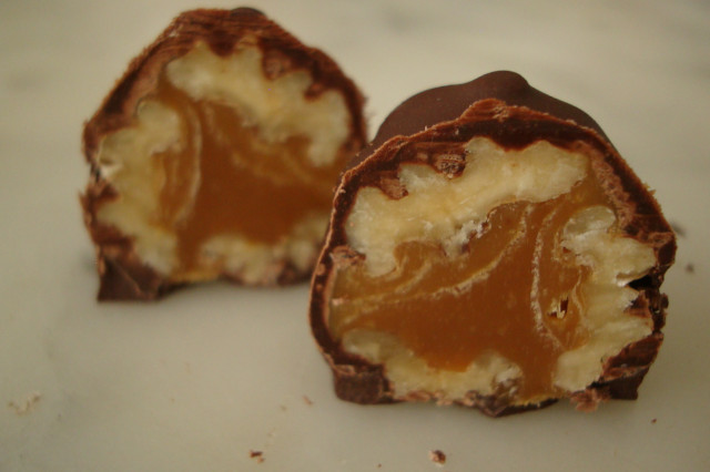 An upclose of a chocoteja cut in half to reveal a pecan caramel filling.