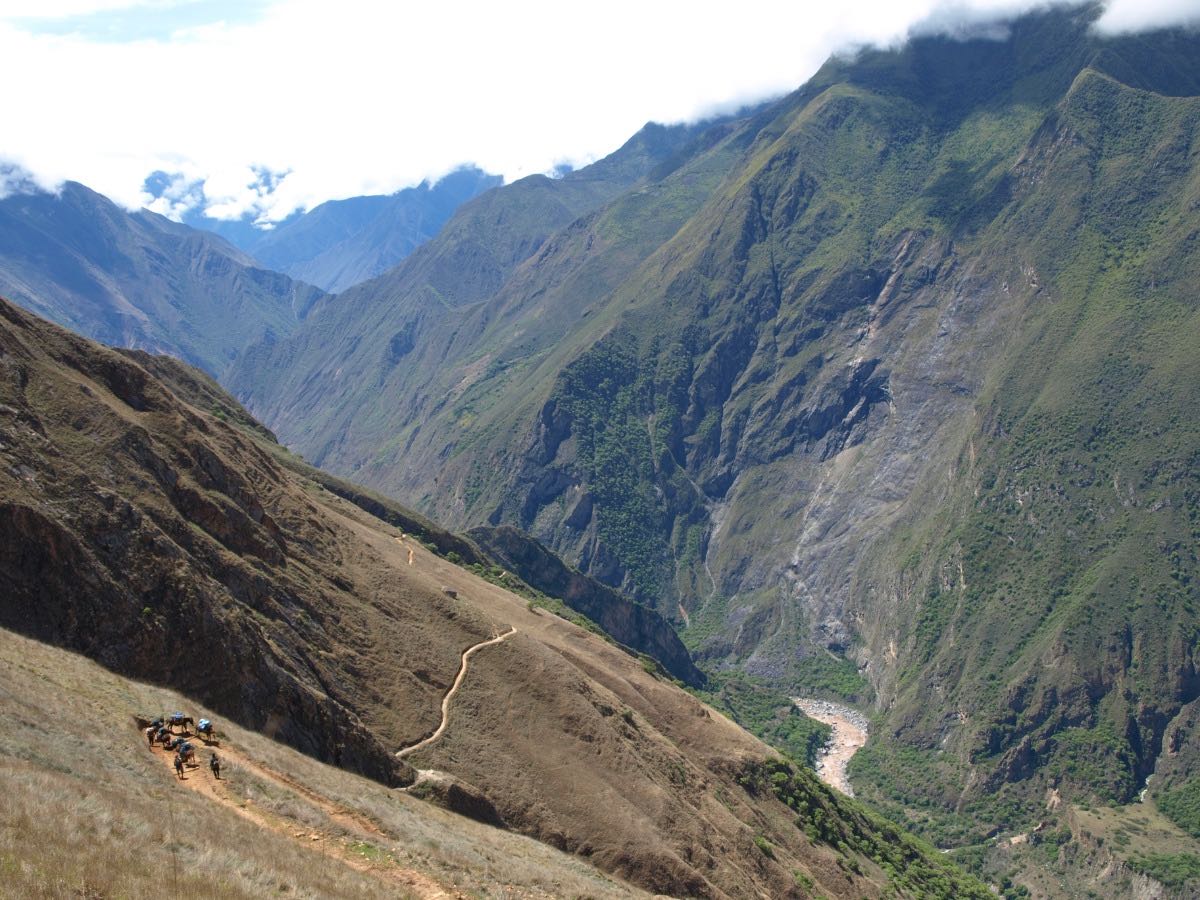 On the left bank of a steep valley a trail zig-zags up the mountainside leading to Choquequirao.