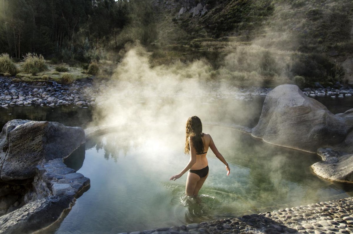 Women entering a hot spring with steam rising from it at Colca Lodge spa resort in Peru.