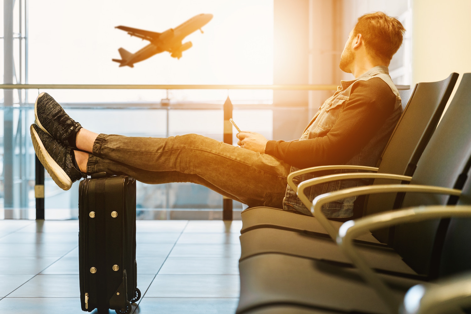 A traveler at the airport watching a plane take off.