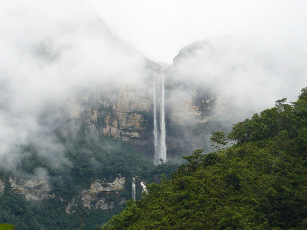 A waterfall surrounded by fog and green landscapes.