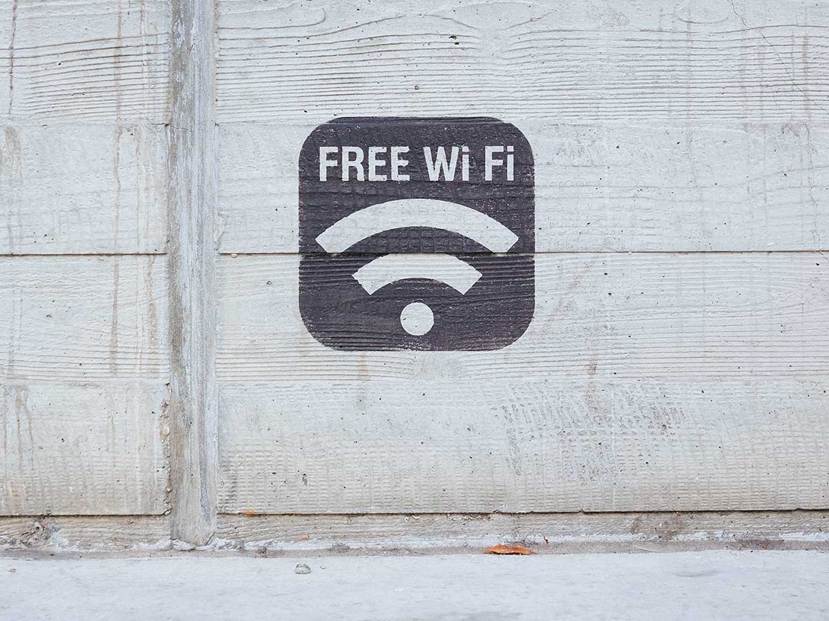 A black square stating "Free WiFi" with a WiFi signal below in white writing on a white wall.