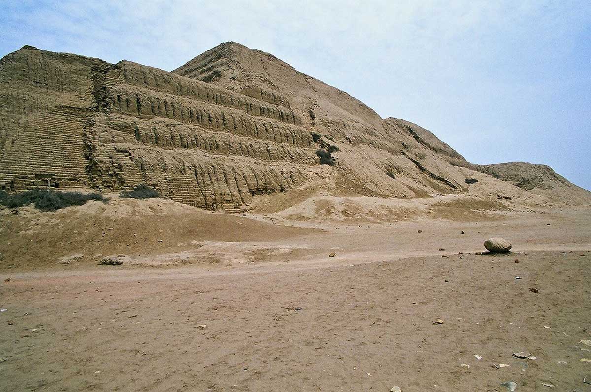 A tall construction of adobe blocks in a dusty desert.