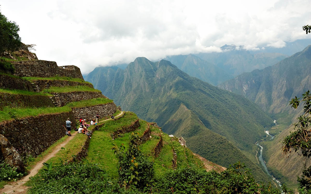 The Inca Trail to Machu Picchu with its green terraced mountainsides on a cloudy day.