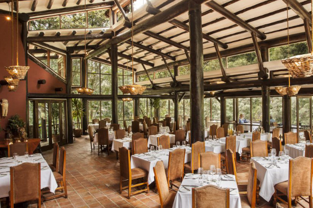 A restaurant with many empty tables and a wall of panoramic windows.