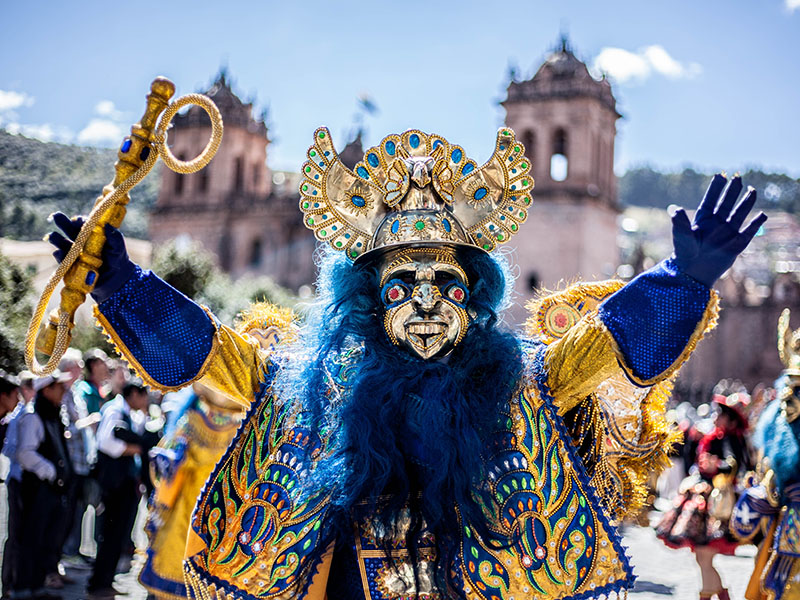 A performer wearing a bright yellow and blue costume at the Inti Raymi festival in Cusco.
