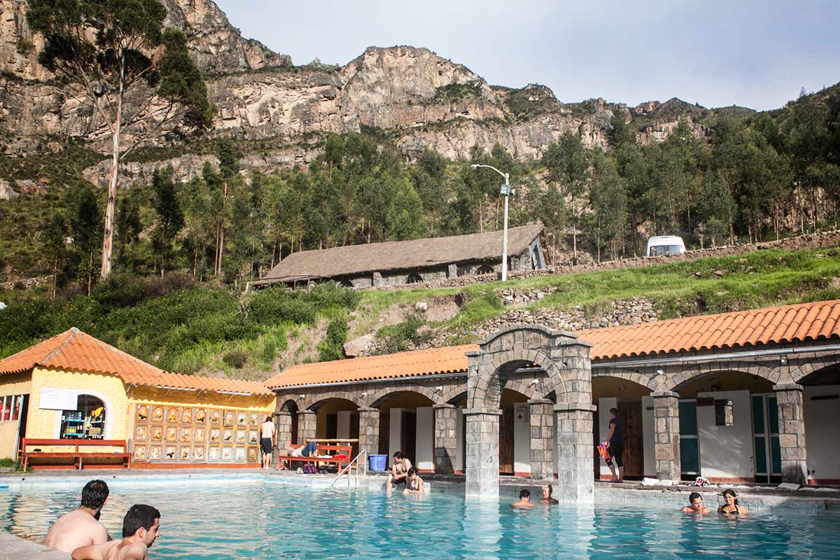 blue pool filled with thermal water in Colca Canyon with trees and mountains behind.