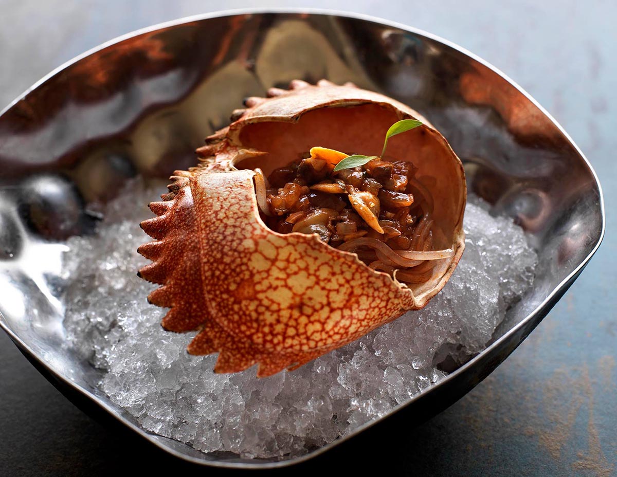 A crab shell served on ice with a clam and crab mixture inside at Maido restaurant in Lima.