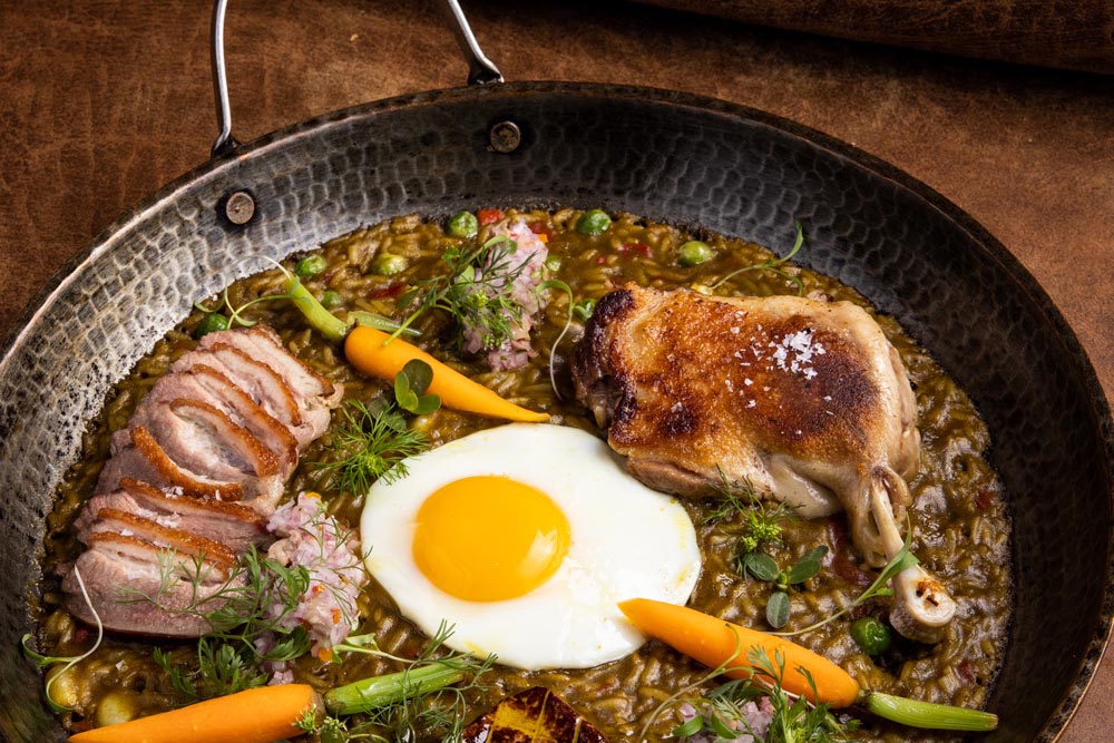 A skillet with various meats, an egg and vegetables at Mayta, one of the best restaurants in Lima.