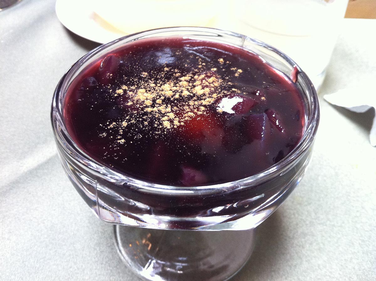 A clear bowl full of a purple Peruvian fruit jelly known as mazamorra morada.