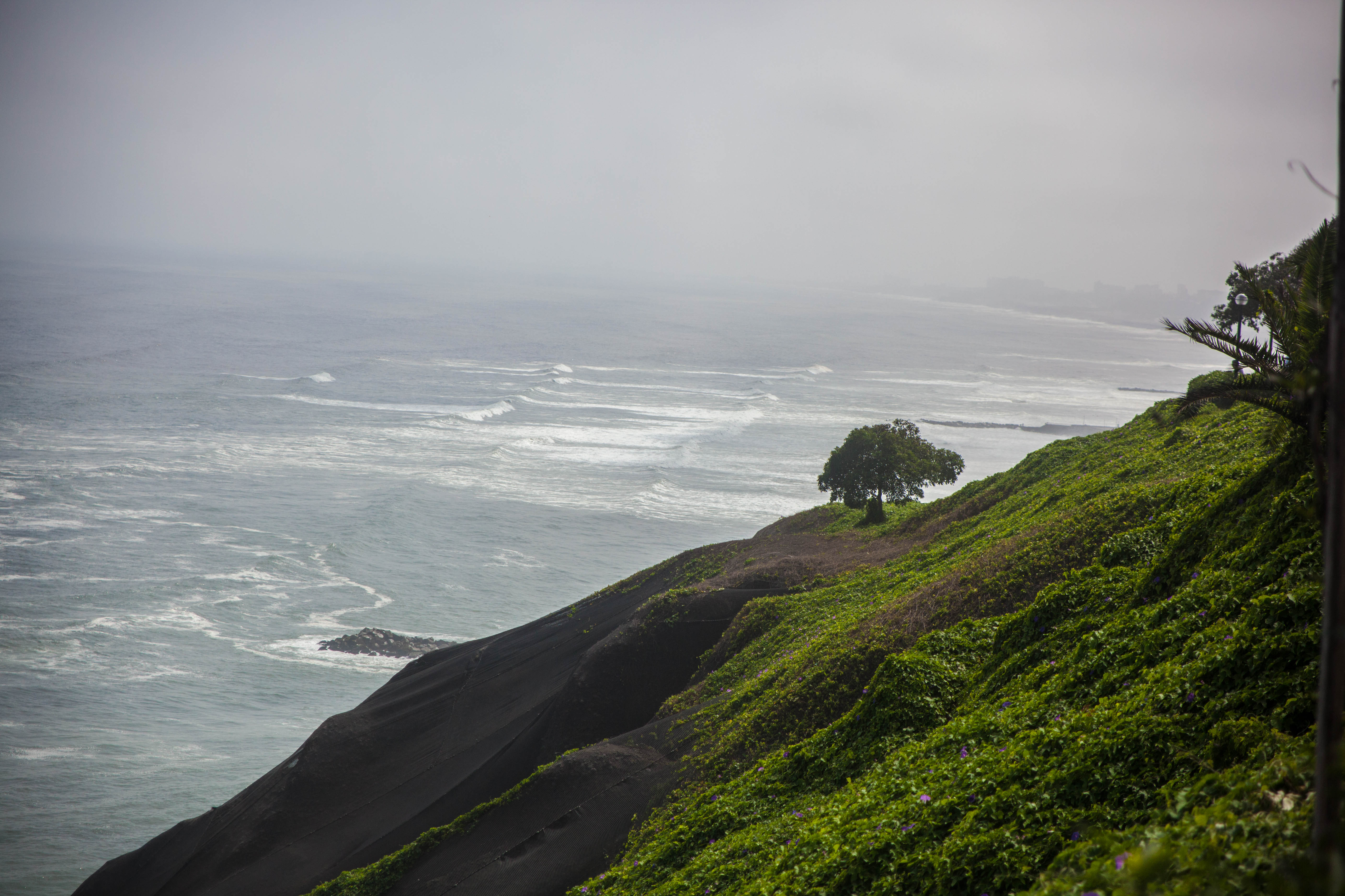 Taken from the Malecon in Lima. Shows the Miraflores beach with several waves on a gray and gloomy day