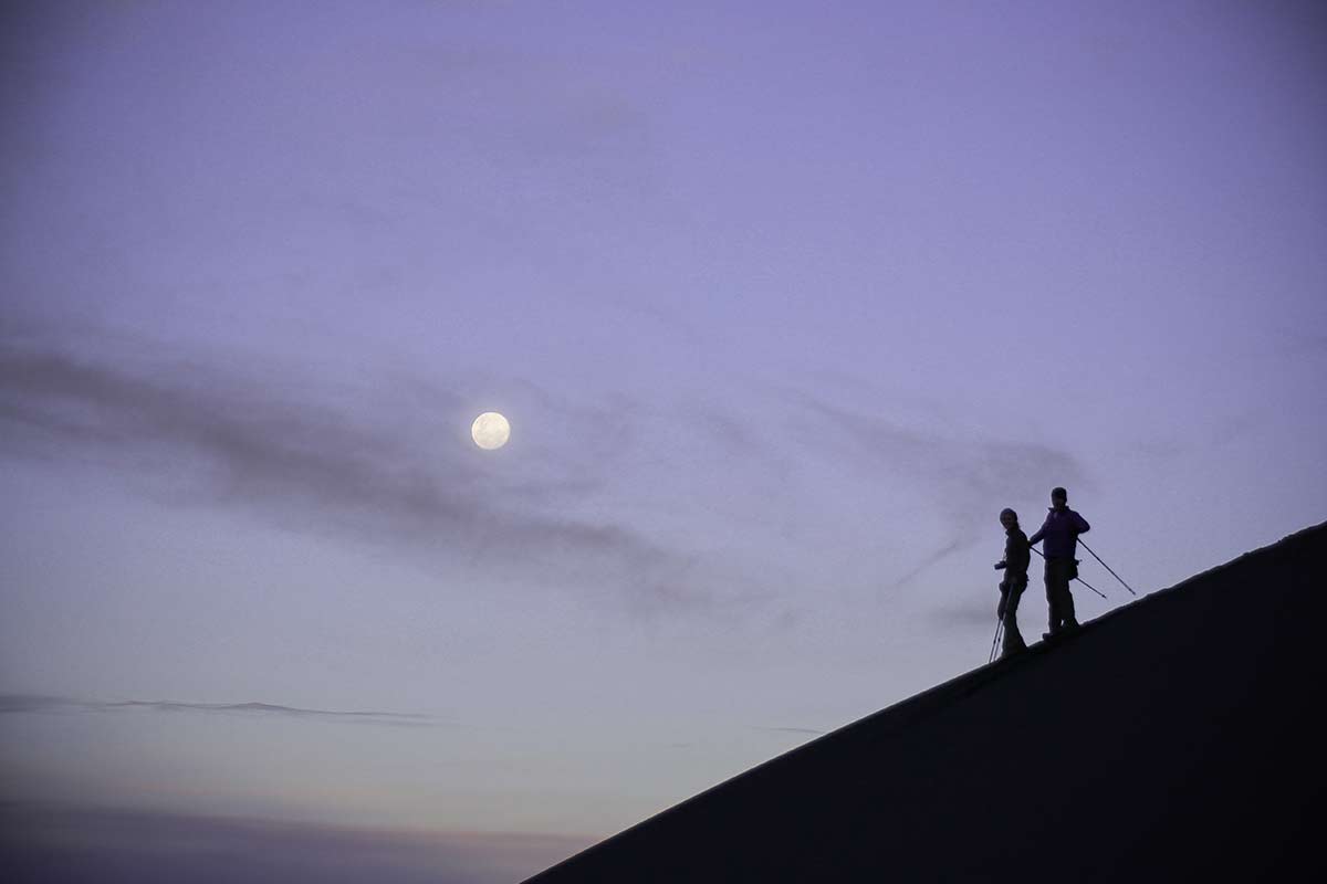 Silhouette of two hikers walking down a volcano in the Salinas and Aguada Blanca National Reserve. 