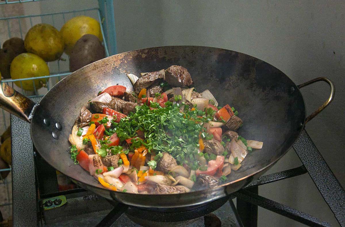 Peruvian lomo saltado being prepared in large pan as part of Exquisito's cooking class.