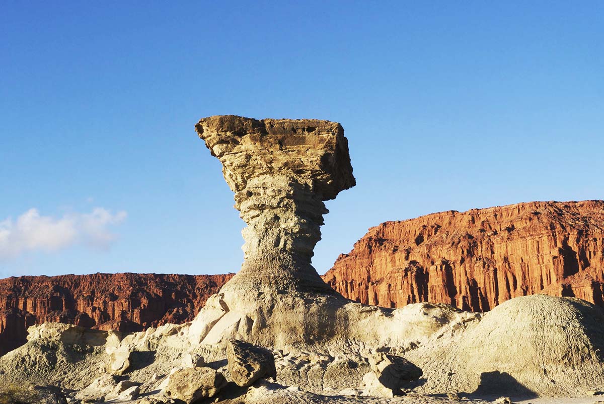 Brown rocks withered away with red hills in the distance in the Monte Desert in South America.