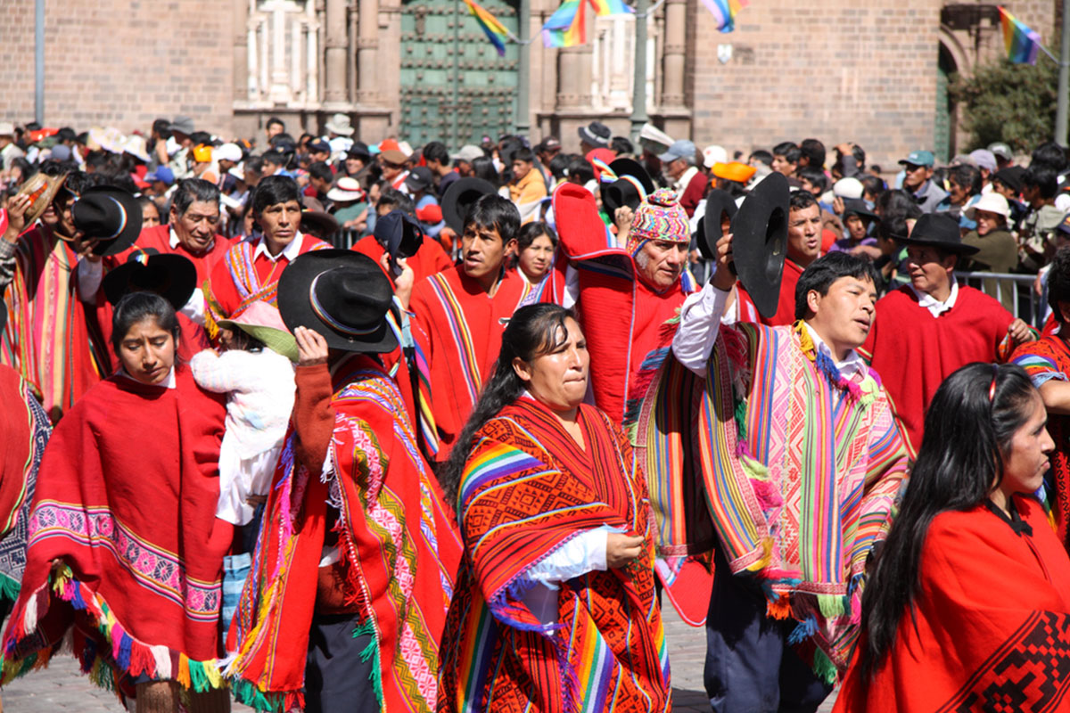 Many local people crowded at the Plaza de Armas in Cusco, Peru. Many of them are wearing red ponchos with streaks of color.