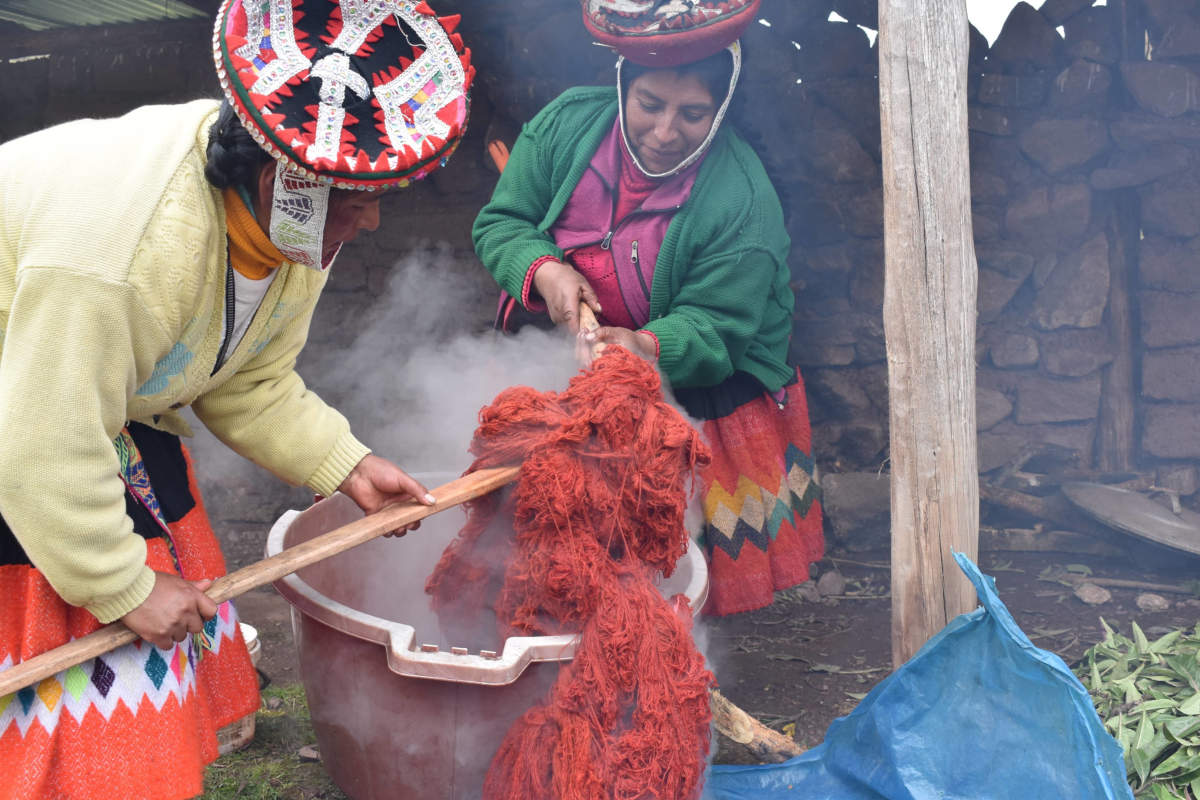 Two Andean women coloring their yarn with natural dyes before weaving traditional Peruvian textiles.