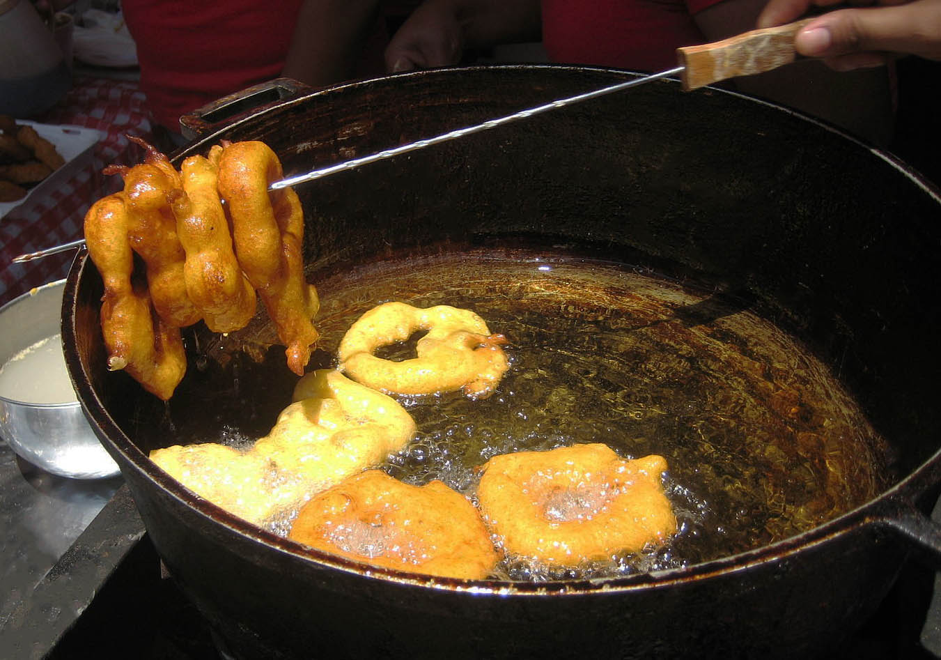 Peruvian dessert, picarones, being fried in a pot of oil.