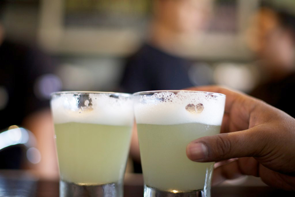 Two glasses with Peru's national drink, the Pisco sour, a yellow frothy cocktail.