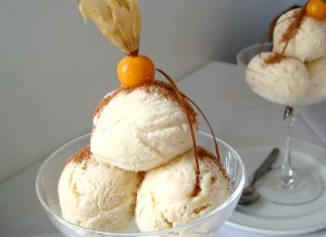 A bowl with 3 scoops of queso helado and a aguaymanto on top