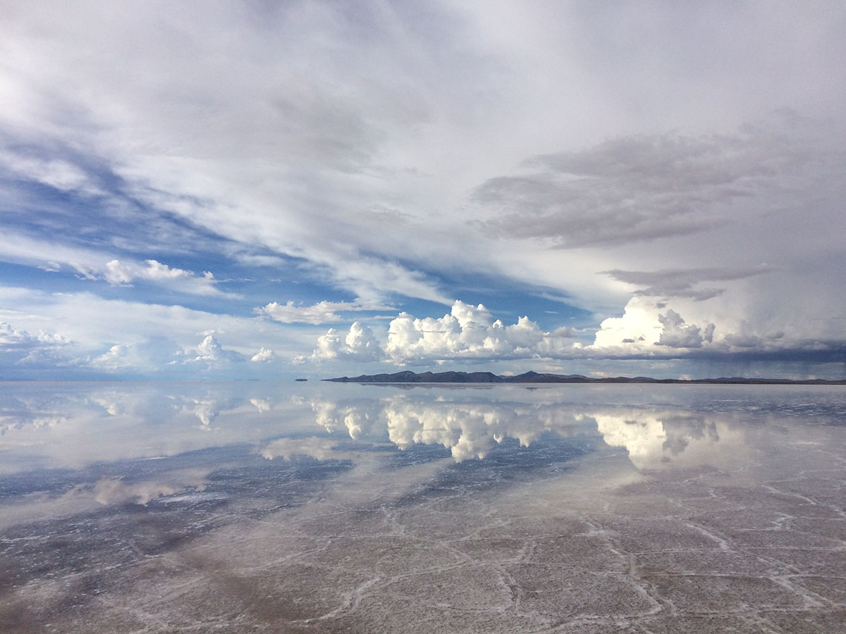 A cloudy sky reflected into the salt flats on the ground at the Uyuni desert.