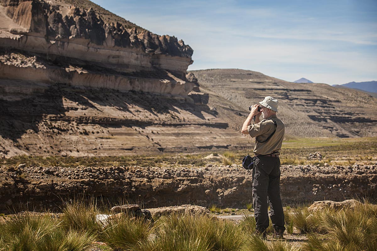 A man looking at a rock formation in the Salinas and Aguada Blanca National Reserve with his camera.