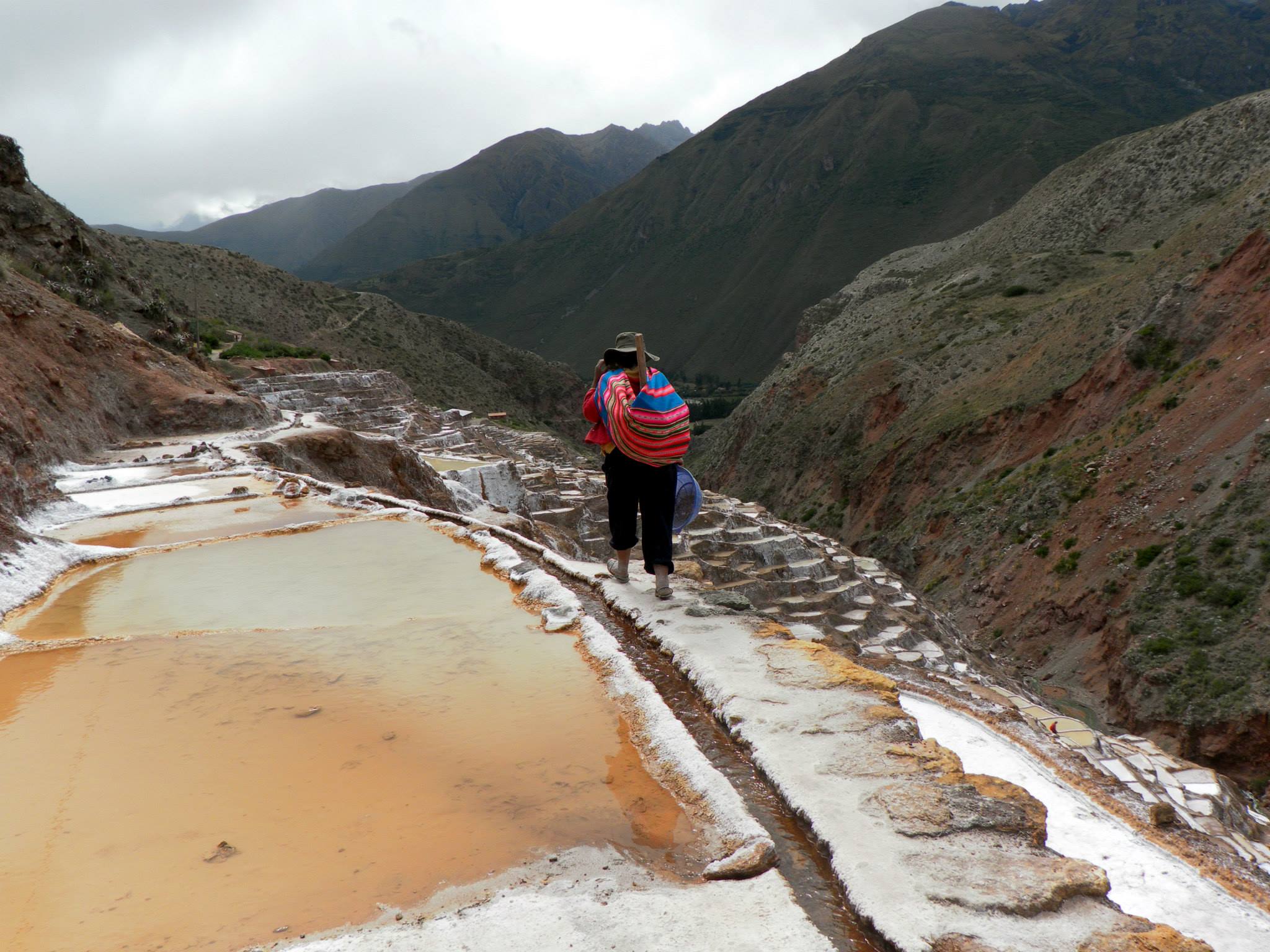 Person with colorful Andean pack full of supplies to start working in the Salt Pans.