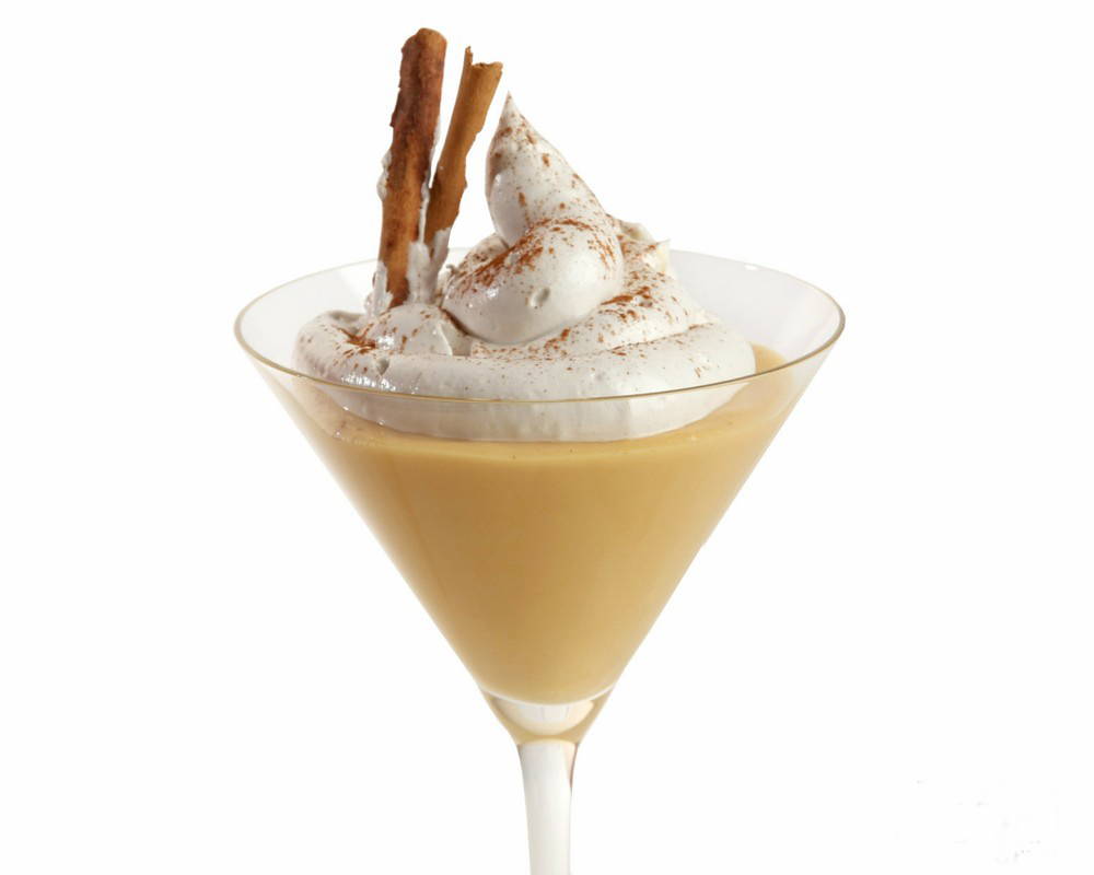 A glass cup with the yolky Peruvian dessert suspiro a limeña, topped with whipped cream and cinnamon